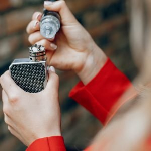 Stylish girl in a city. Lady use the electronic cigarette. Woman in a red jacket.
